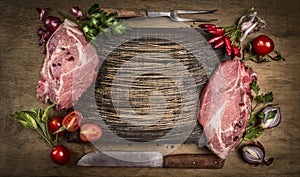 Raw pork meat chops with kitchen tools, fresh seasoning and ingredients for cooking rustic wooden background, top view, frame.