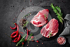 Raw pork meat. Fresh steaks on slate board on black background