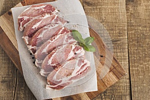 Raw pork meat with spices, wooden cutting board. Food Cooking Ingredient. Top view with copyspace.