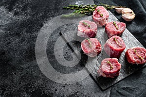 Raw pork medallion steaks with pepper and thyme. black background. Top view. Copy space