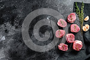 Raw pork medallion steaks with pepper and thyme. black background. Top view. Copy space