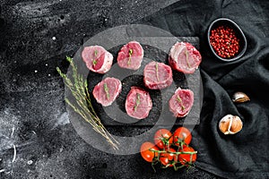 Raw pork medallion steaks with pepper and thyme. black background. Top view