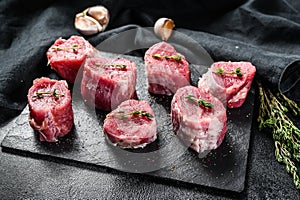 Raw pork medallion steaks with pepper and thyme. black background. Top view