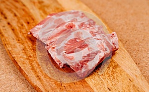 raw pork ribs, cut into pieces on a wooden cutting board.