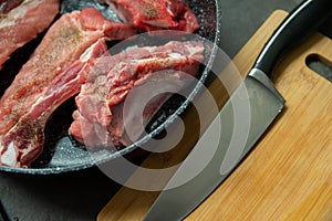 Raw pork ribs are fried in oil in a frying pan