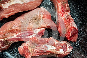 Raw pork ribs are fried in oil in a frying pan