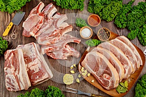 Raw pork ribs with spices and sliced meat on wooden background