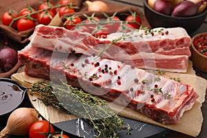 Raw pork ribs with thyme and peppercorns on table, closeup