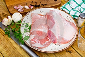 Raw pork secreto fillet and condiments prepared for roasting on plate