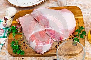 Raw pork secreto fillet and condiments prepared for roasting on wooden cutting board