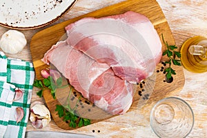 Raw pork secreto fillet and condiments prepared for roasting on wooden cutting board photo