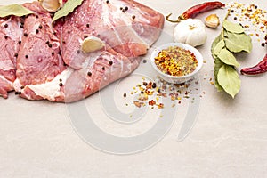 Raw pork shoulder with spices. Bay leaf, garlic. On a stone background