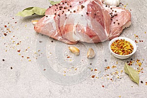 Raw pork shoulder with spices. Bay leaf, garlic. On a stone background