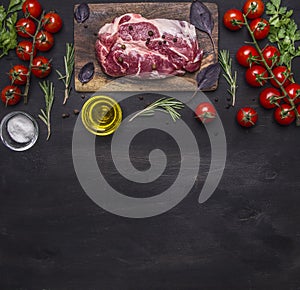 Raw pork steak for the grill, on a cutting board with vegetables and herbs, rosemary border ,place for text on wooden rustic back