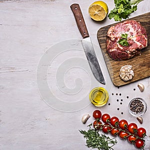Raw pork steak with spices, garlic and herbs, lemon and butter knife for meat, tomatoes a branch, black pepper, dill, border, w