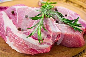 Raw pork steak with spices on a round board With spices and rosemary