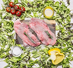 Raw pork steak on vintage cutting board with lettuce, cherry tomatoes, bell pepper, oil spices wooden rustic background top