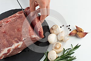 Raw pork tenderloin is sliced â€‹â€‹on a board for cooking.Pork, mushrooms, rosemary, garlic