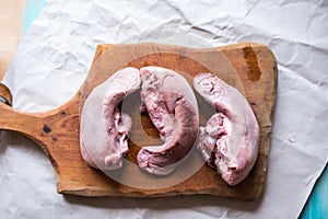 Raw pork tongues on a wooden board