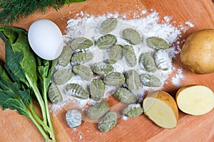 Raw potato gnocchi with spinach in flour, ingredients, top view photo