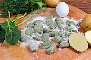 Raw potato gnocchi with spinach in flour on wooden board photo