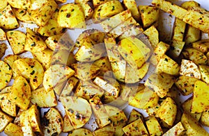 Raw potato slices in spices top view, close up. Fresh potato wedges mixed with herbs and spices ready to be baked or roasted. Raw