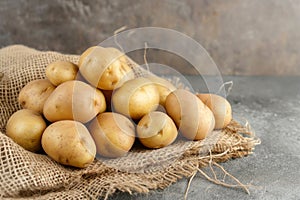 Raw potatoes. Pile of fresh potatoes in an old sack on wooden background. Vegan diet, healthy organic food, vegetables, salad