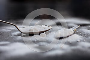 Raw powdered baking soda in a antique spoon on wooden surface