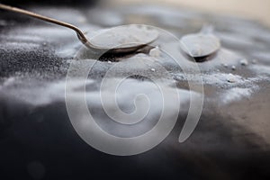 Raw powdered baking soda in a antique spoon on wooden surface