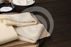 Raw puff pastry dough on wooden table, closeup. Space for text