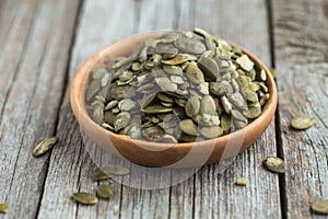 Raw Pumpkin seeds close up in wooden bowl