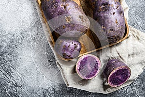 Raw purple potatoes on a chopping Board. Gray background. Top view. Space for text