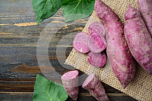 Raw purple sweet potatoes on wooden background