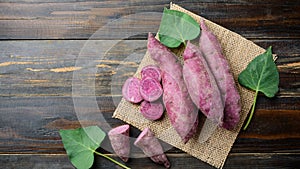 Raw purple sweet potatoes on wooden background