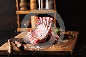 Raw rack of lamb with spices on a cutting board