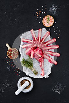 Raw rack of lamb on wrapping paper with herbs and seasoning