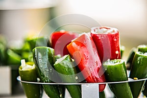 Raw red and green organic peppers in a glass bowl ready to cook