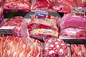 Raw red meat slices on a butcher shop shelf with price tags