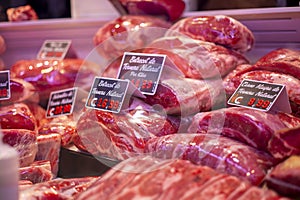 Raw red meat slices on a butcher shop shelf with price tags