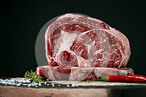 Raw rib eye beef steak on a black background