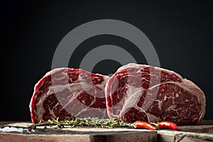 Raw rib eye beef steak with pepper and herbs