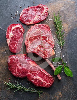 Raw Rib eye steak or beef steak on the graphite board with herbs and spices