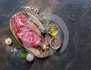 Raw Rib eye steak or beef steak on the graphite board with herbs and spices