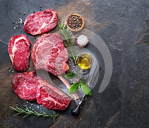 Raw Rib eye steak or beef steak on the graphite board with herbs and spices