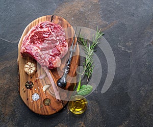 Raw Rib eye steak or beef steak on the graphite board with herbs and spices