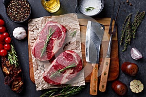 Raw ribeye beef steak with herbs on cutting board