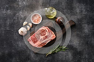 Raw ribeye steak on a wooden board. Preparing raw beef steak for barbecue grill