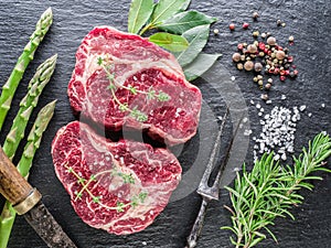 Raw Ribeye steaks or beef steak on graphite tray with herbs