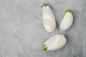 Raw ripe white color eggplants on grey background, top view. Healthy vegetarian diet food