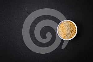 Raw risoni pasta made from durum wheat on a dark concrete background